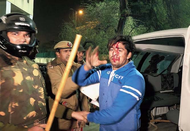 Police detain an injured student outside Jamia Millia Islamia university on Sunday night
